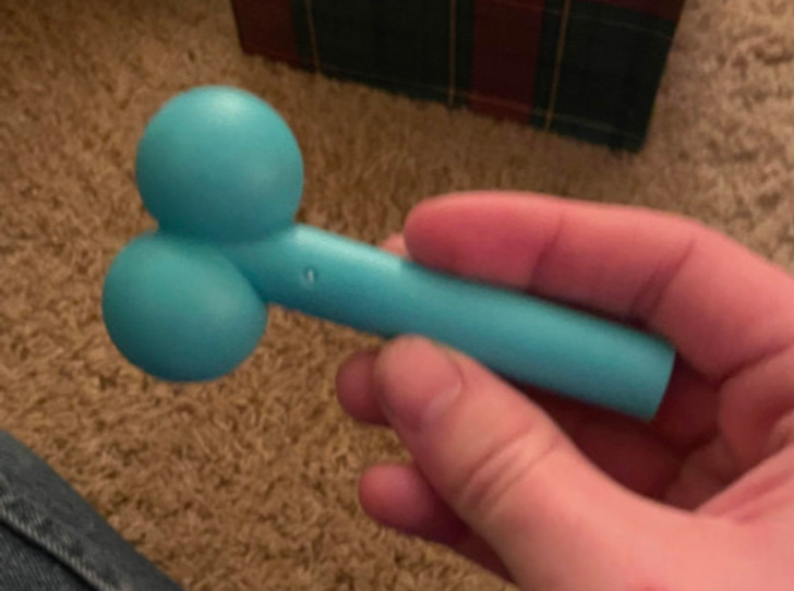 Closeup of a hand holding a blue toy, sitting on a carpet.